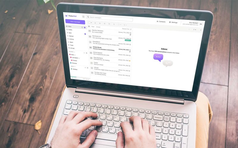 Hands on a laptop computer checking Proton Mail.