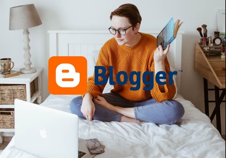 A person sitting on a bed creating a Blogger website on a laptop