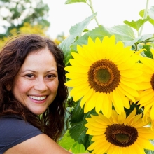 Woman smiling next to sunflowers